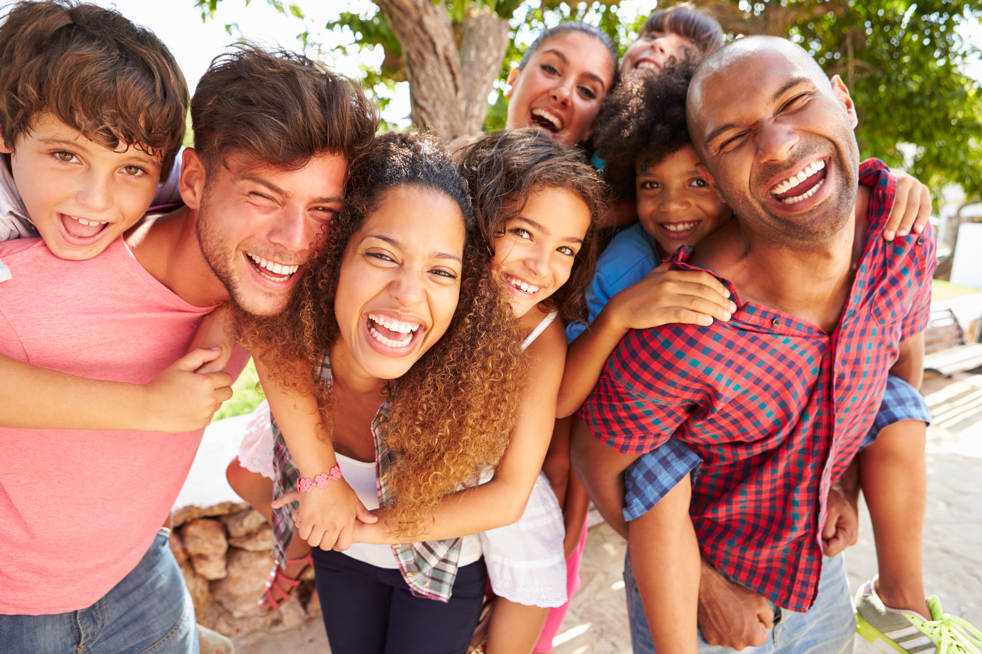 Group Of Parents Giving Children Piggyback Ride Outdoors