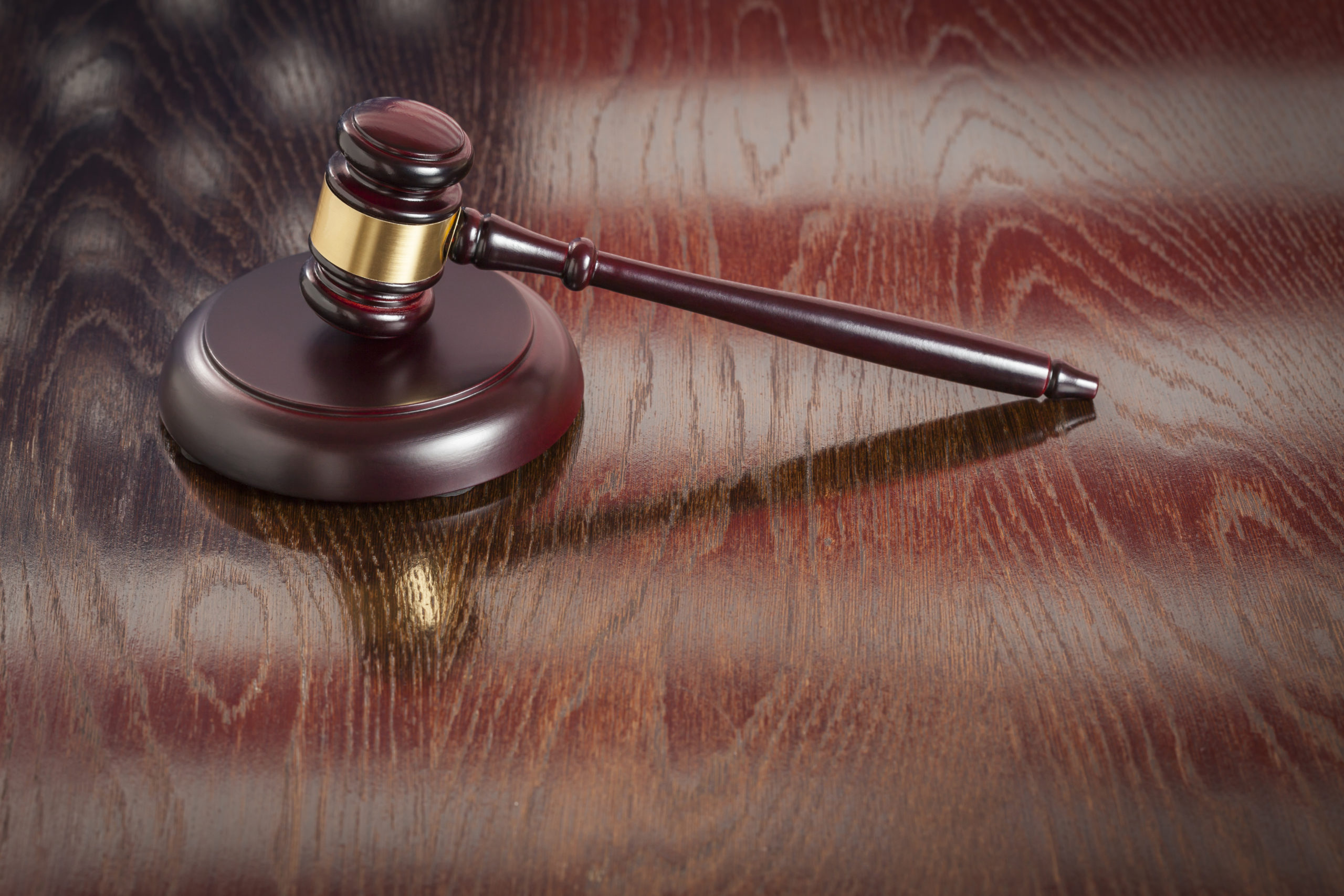 Wooden Gavel Resting on American Flag Reflecting Table.