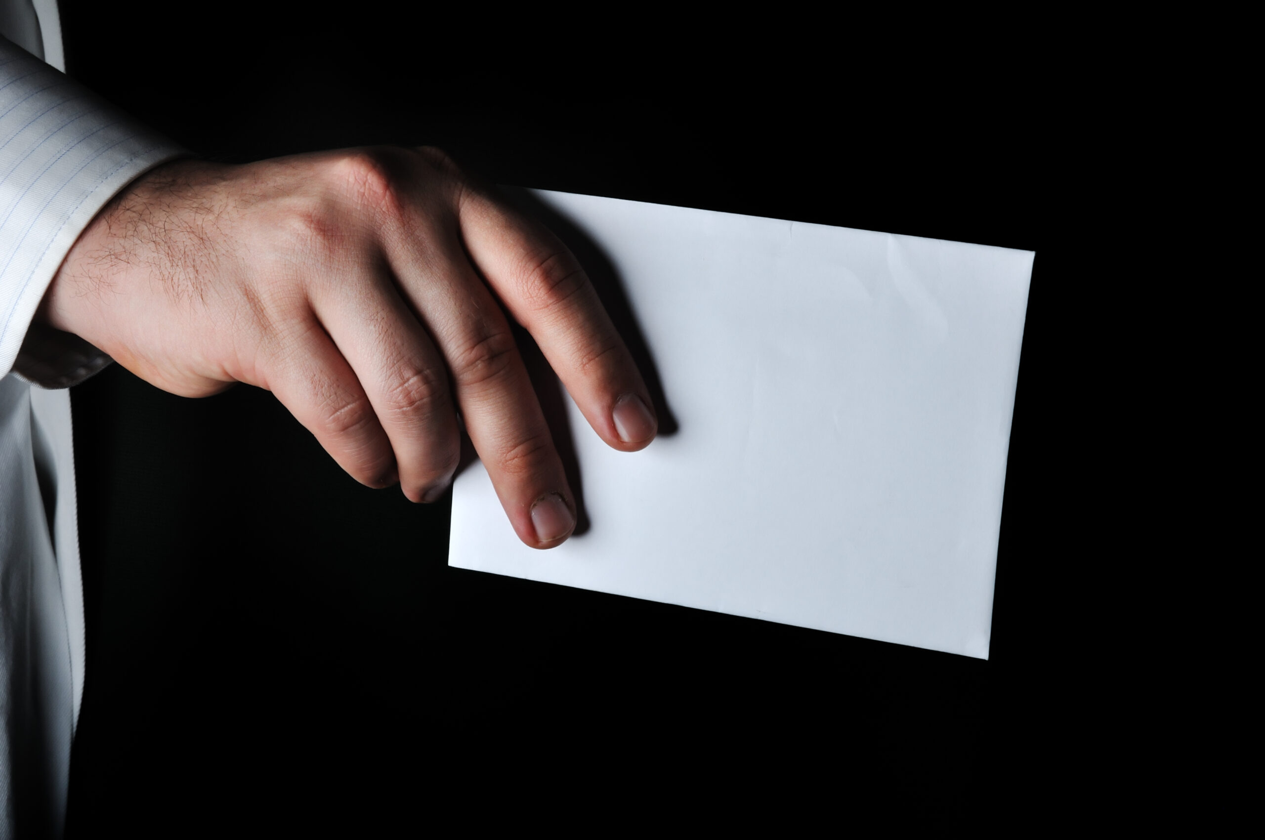 Hand holding a white envelope with dark background